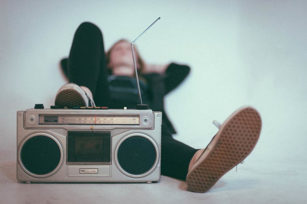 Person lies down and rests foot on radio