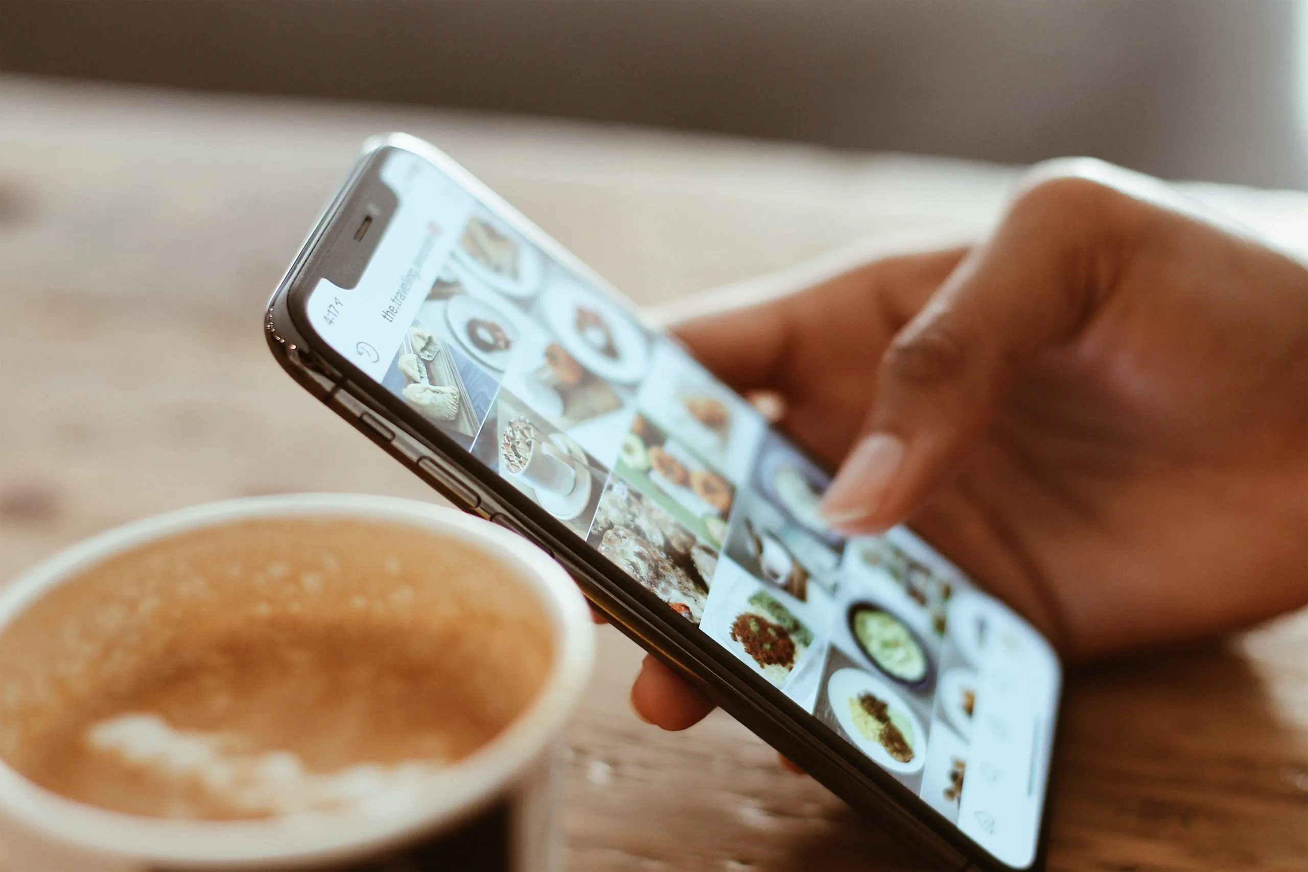 retail marketing tips: person scrolling on phone at coffee shop