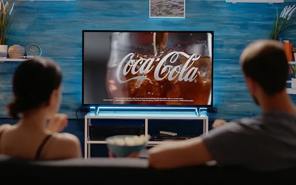 retail marketing tips: people sitting on couch watching coke commercial on tv