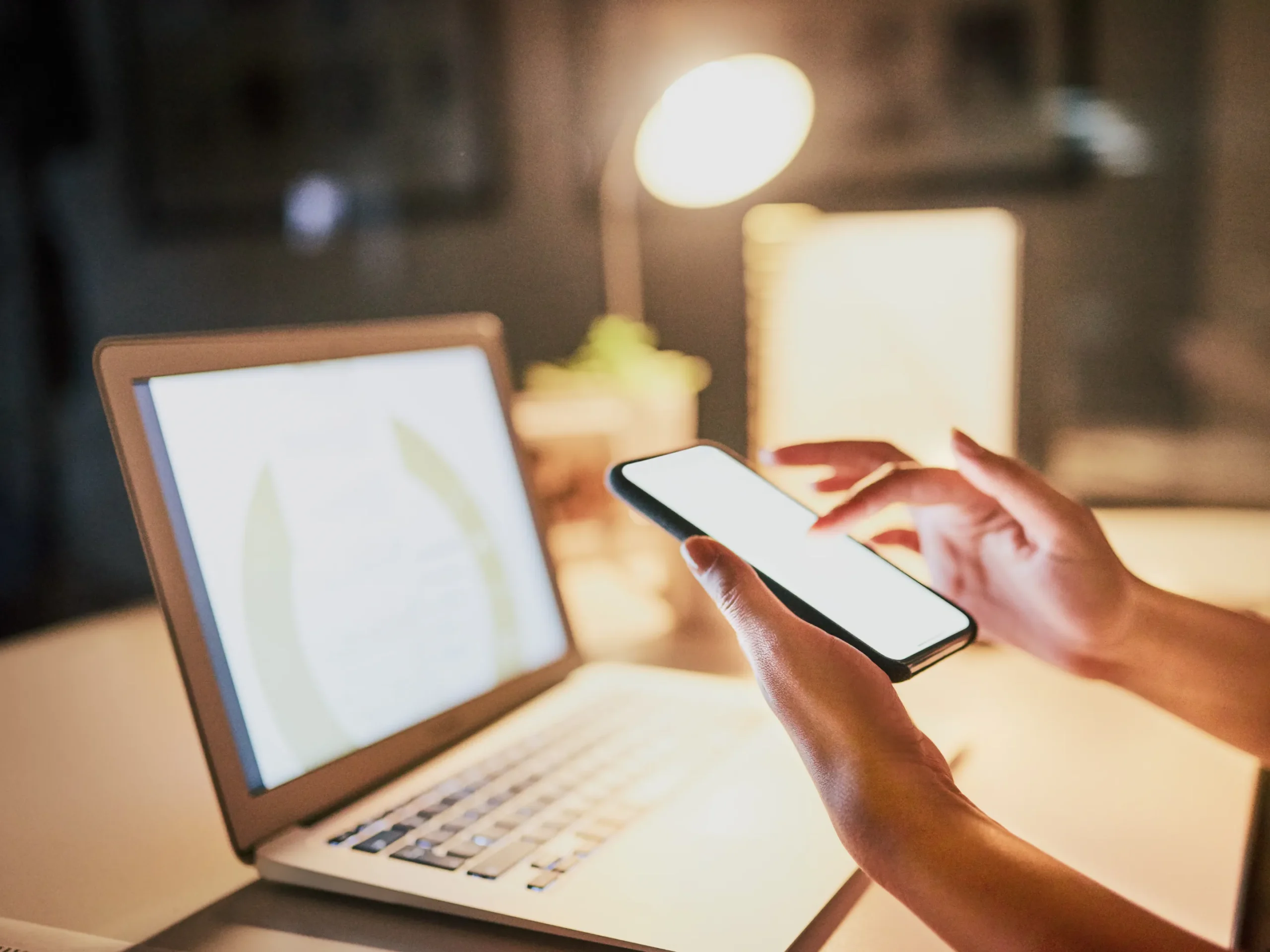 hand holding phone in front of a laptop - representation of media
