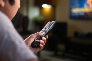 Man holds tv remote while watching tv