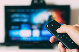Measure TV Advertising - Hand holds remote control in front of tv