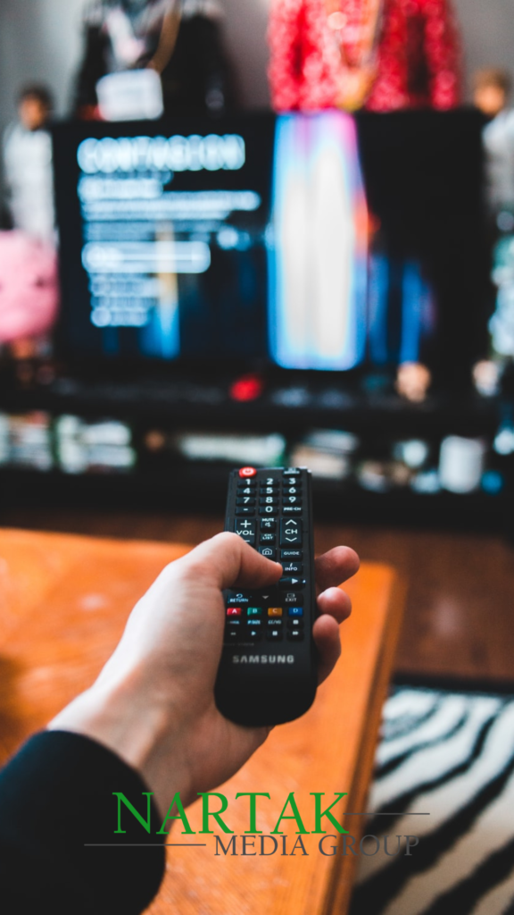 man holding a TV remote pointing at the TV