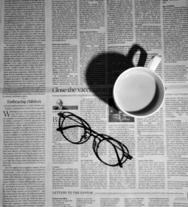 Glasses and coffee sit on newspaper