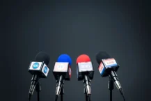 Understanding Political Media Buying Cover - four news microphones in front of black background