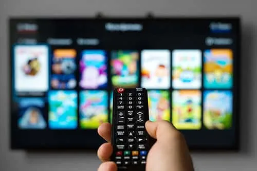 Hand holding a remote pointing to a smart TV
