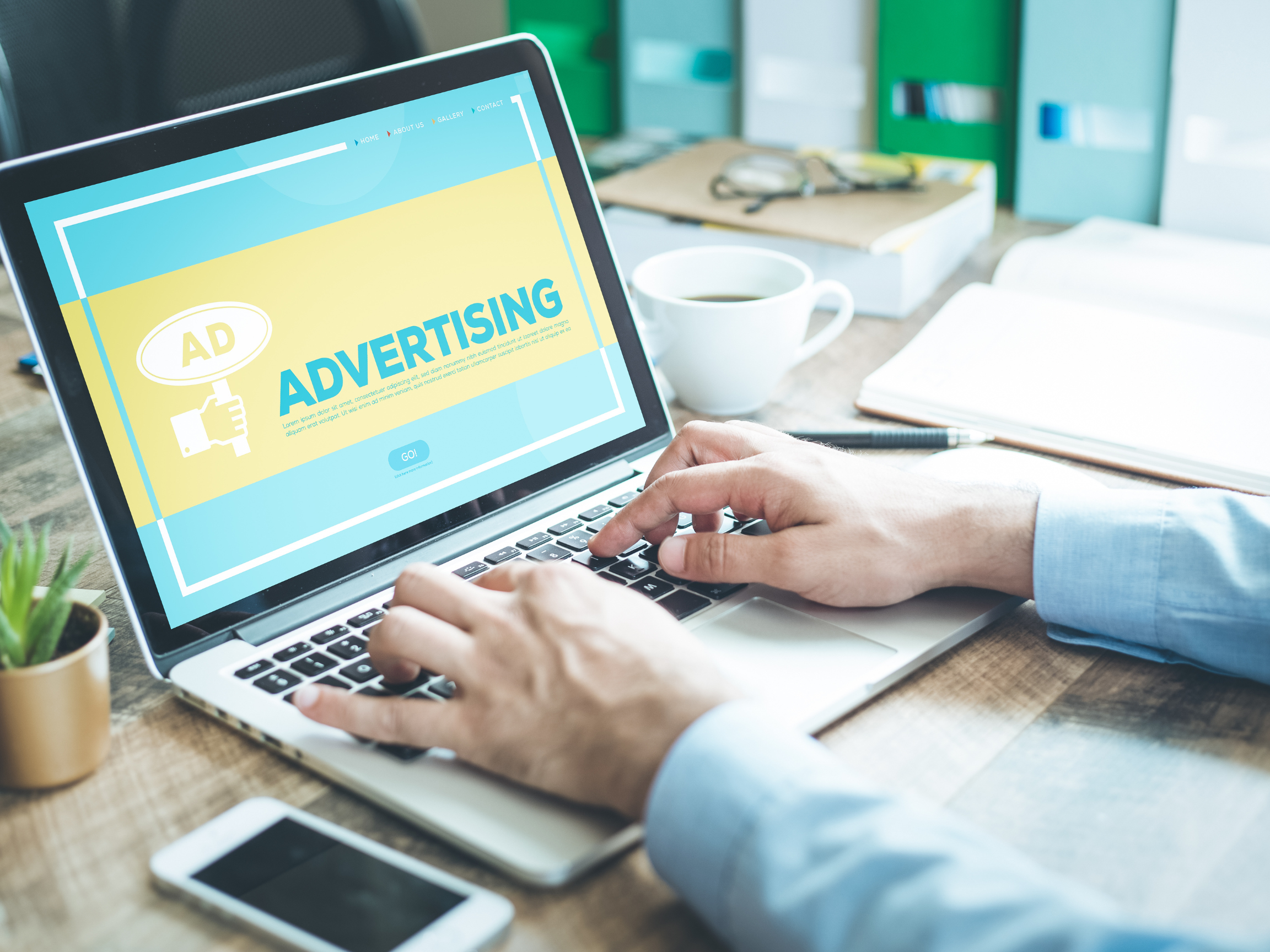 person working on laptop with a design saying "advertising"