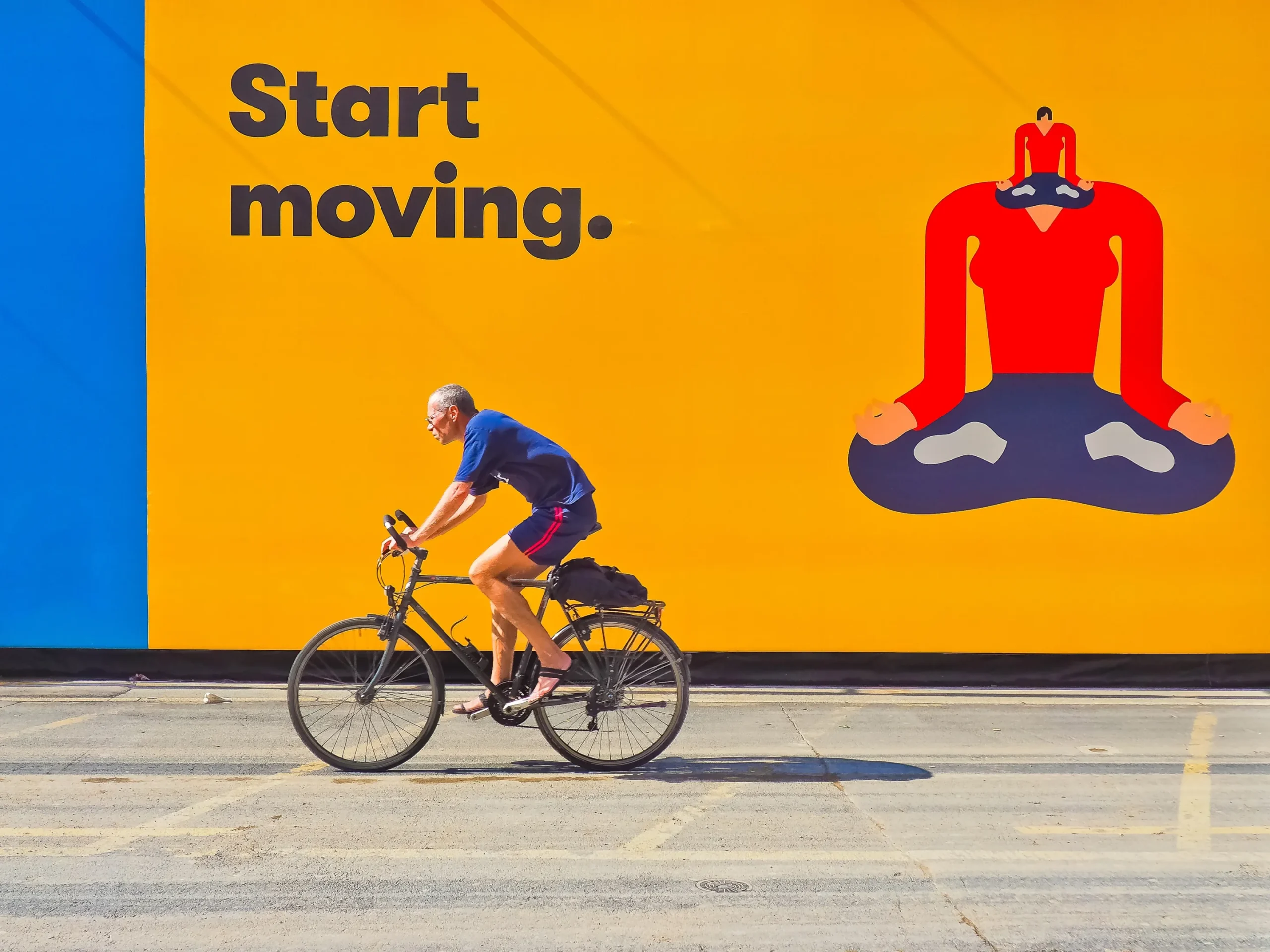 person riding bike in front of a wall advertisement