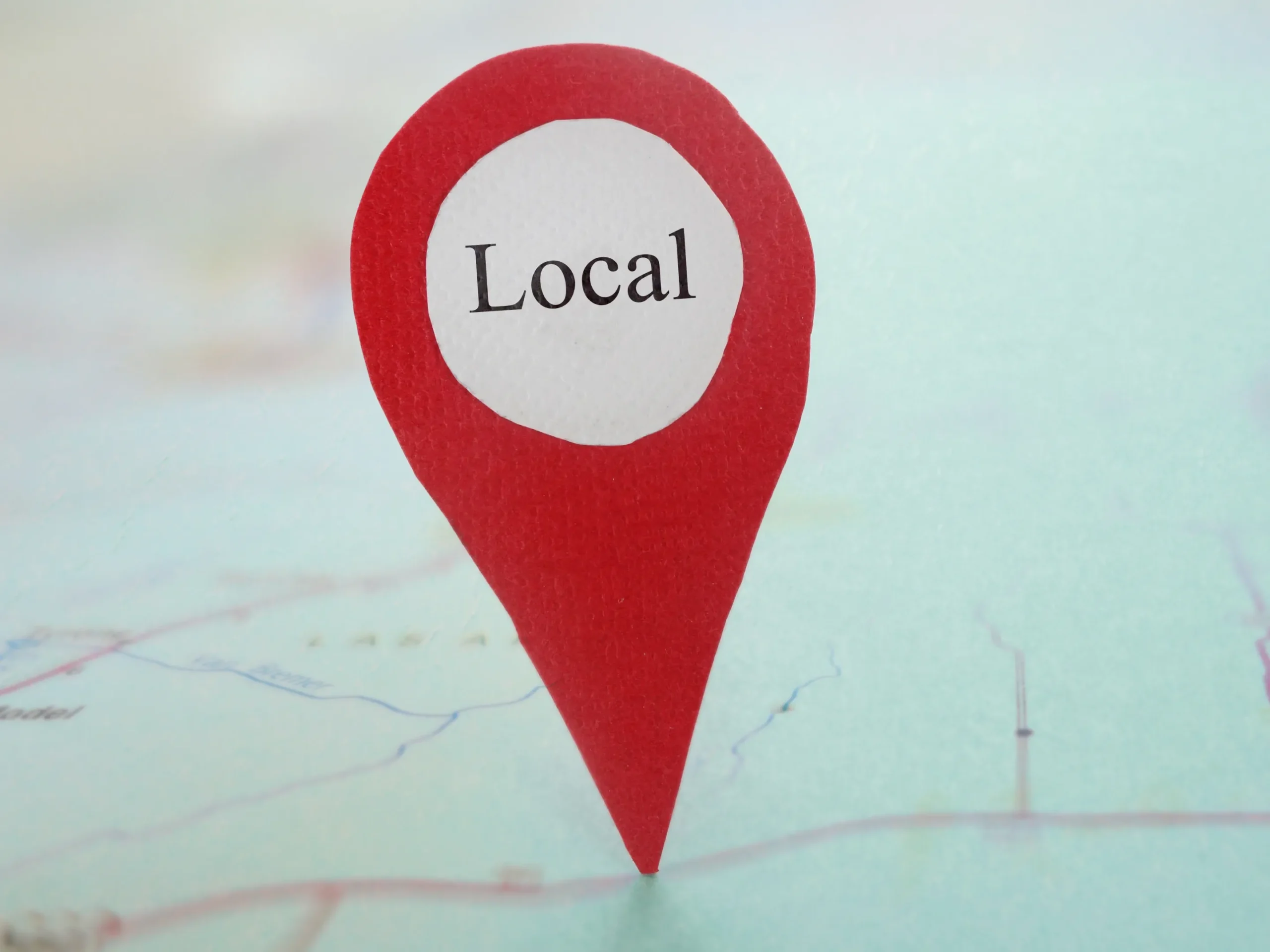 paper cutout of a location pin that says "location" on it - placed on a map