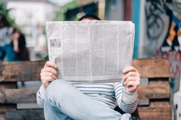 Print advertising services with newspaper advertising agency - man reads newspaper while sitting on park bench