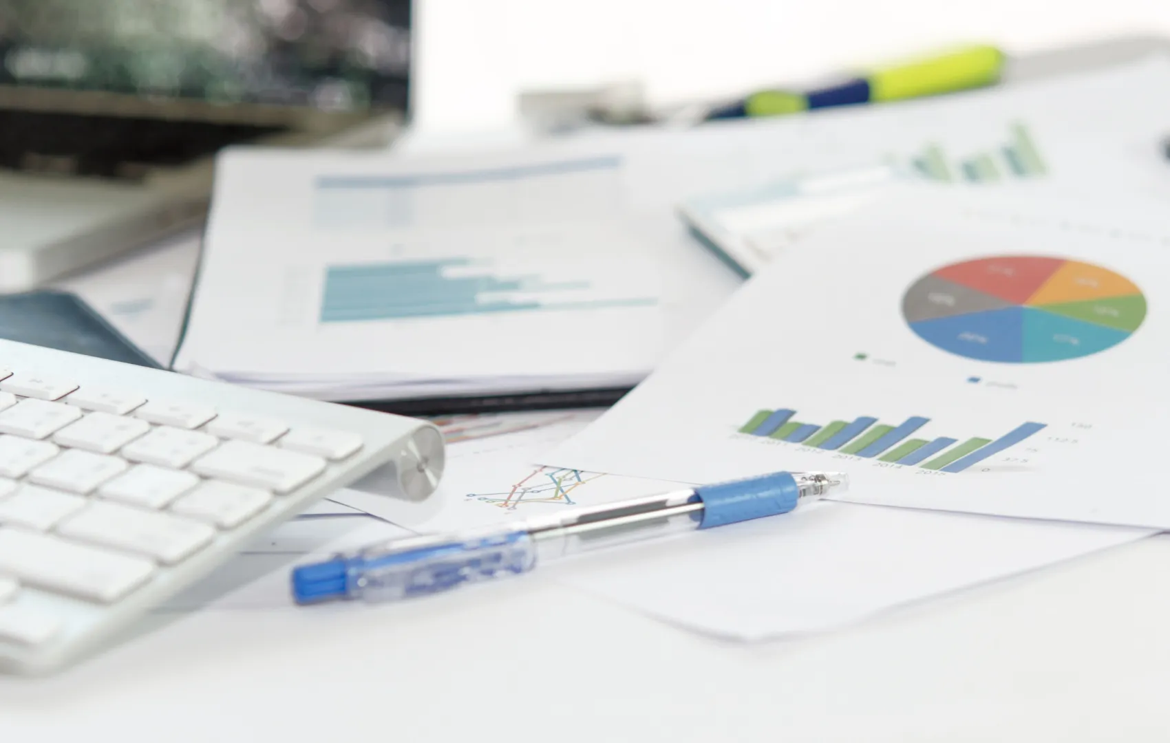 Marketing funnel and analytics sheets scattered on desk with pen and keyboard